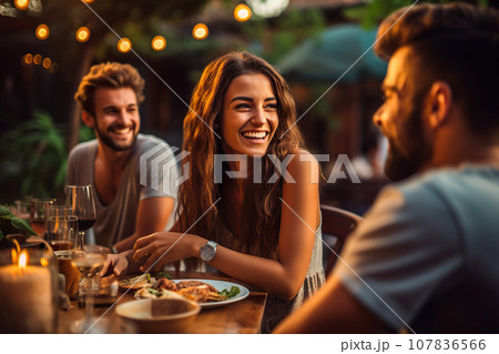 A Group of Friends Share Laughter and Delight as They Enjoy a Scrumptious Dinner at an Outdoor Restaurant. created with Generative AI 107836566