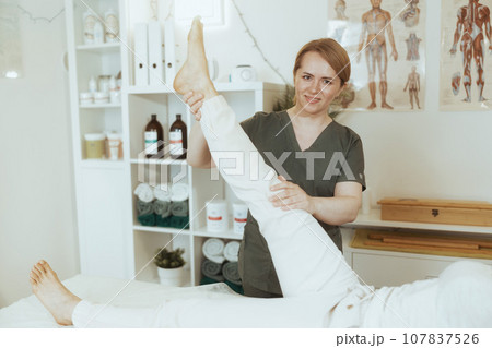 female therapist in massage cabinet conducting examination 107837526