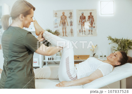 happy therapist woman in massage cabinet conducting examination 107837528
