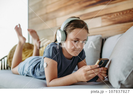 Diabetic girl watching social media content on smart phone.The CGM device makes life of schoolgirl. easier, helping manage illness and focus on other activities. 107837827