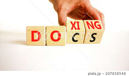 Docs or doxing symbol. Concept words Docs Doxing on wooden block. Beautiful white table white background. Businessman hand. Business docs or doxing concept. Copy space. 107838548
