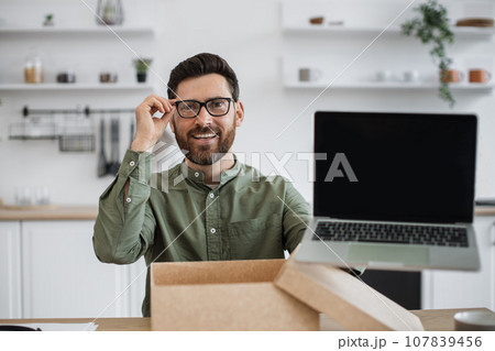 Male blogger doing unpacking of new portable laptop at home 107839456