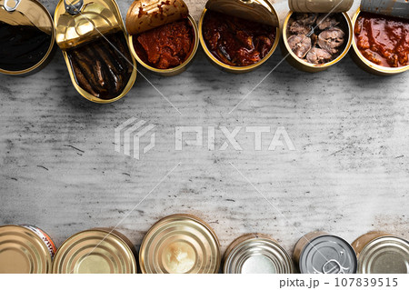 Top view of opened cans with fish conserves on wooden background Top view of opened cans with fish conserves on wooden background 107839515