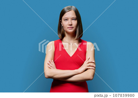 Portrait of young confident woman in red on blue studio background Portrait of young confident woman in red on blue studio background 107839980