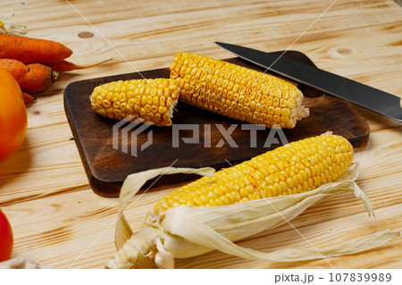 Cobs of corn on wooden cutting board 107839989