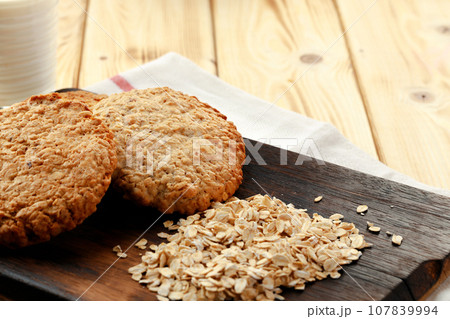 Oat cookies and oat flakes on wooden surface Oat cookies and oat flakes on wooden surface 107839994