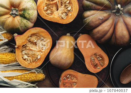 Corn cob and pumpkin on brown wooden board 107840037