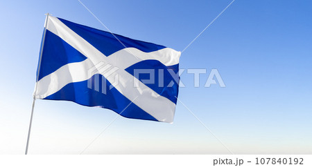 Flag of Scotland waving against blue sky 107840192