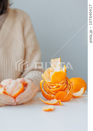 European woman cleans tangerines with her hands at home. citrus vitamins to boost immunity European woman cleans tangerines with her hands at home. citrus vitamins to boost immunity 107840417