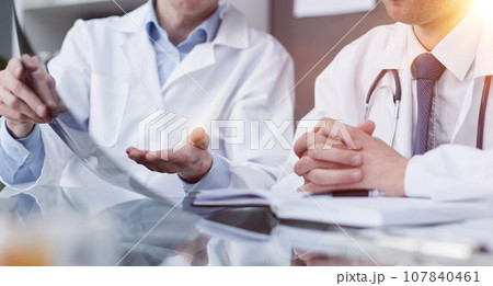 Two doctors look at x-rays and discuss the diagnosis. They sit a 107840461