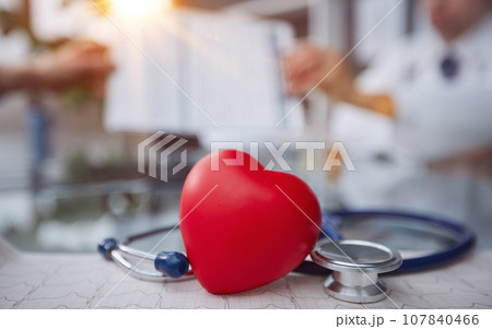 Stethoscope and red heart on wooden table. Cardiology concept Stethoscope and red heart on wooden table. Cardiology concept 107840466