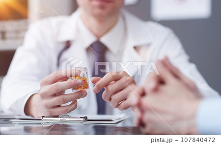 doctor pointing his finger at the pills at the table 107840472