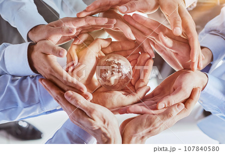 Many different hands are holding planet Earth. 107840580