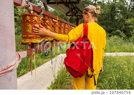 Person pilgrim woman touching turning spinning Buddhist prayer wheel at Buddhist monastery. Prayer wheels in Buddhist stupa temple. Buddhism religion concept Person pilgrim woman touching turning spinning Buddhist prayer wheel at Buddhist monastery. Prayer wheels in Buddhist stupa temple. Buddhism religion concept 107840759