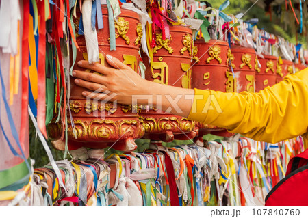Person pilgrim female hand touching turning spinning Buddhist prayer wheel at Buddhist monastery. Prayer wheels in Buddhist stupa temple. Buddhism religion concept Person pilgrim female hand touching turning spinning Buddhist prayer wheel at Buddhist monastery. Prayer wheels in Buddhist stupa temple. Buddhism religion concept 107840760