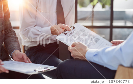 Close-up of businessmen looking at contract close-up while sitting 107840778