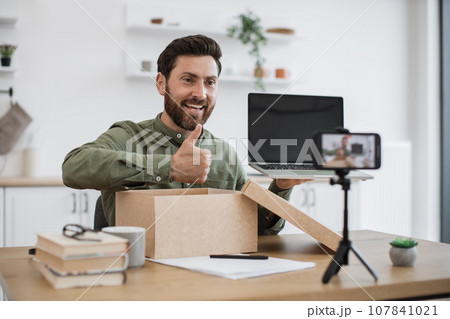 Blogger unpacking box with new laptop and recording video 107841021