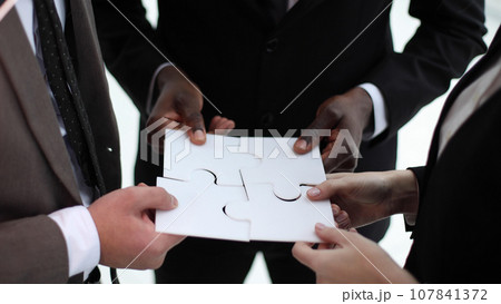 Business teamwork with white puzzle of four pieces cooperation unity concept 107841372