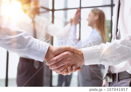 Business colleagues shaking hands in an office hallway 107841957