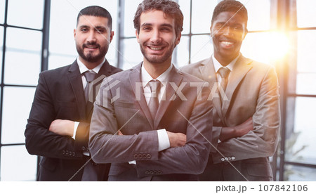 three colleagues stand in the lobby of a modern office with their arms crossed three colleagues stand in the lobby of a modern office with their arms crossed 107842106