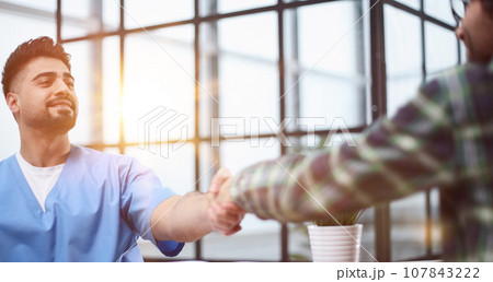 Cheerful male patient and doctor shaking hands. 107843222