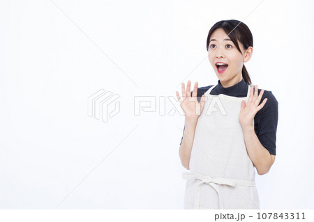 白い背景の前で笑顔でビックリしている30代の主婦 107843311