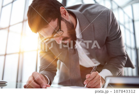 a man puts his signature on legal documents, makes an investment deal 107843312