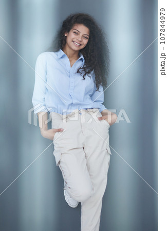 Smiling attractive young business woman in blue shirt posing on gray background 107844979