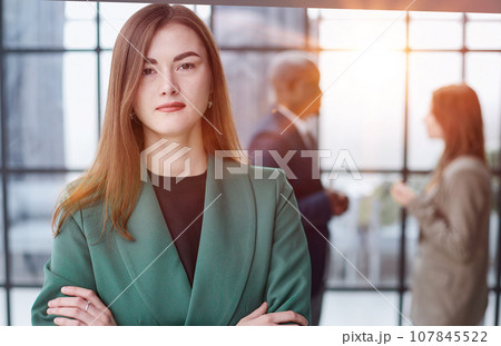 Portrait of a confident young businesswoman standing with her arms crossed in an office Portrait of a confident young businesswoman standing with her arms crossed in an office 107845522