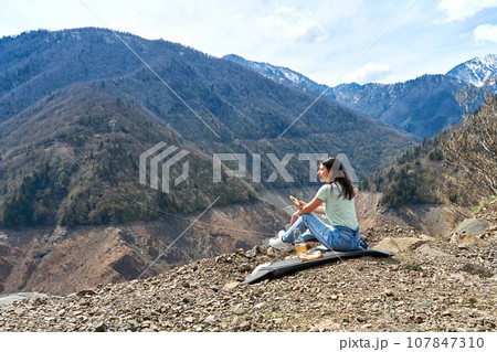 A girl on a picnic with an incredible natural view of the mountains and a dehydrated mountain river. Gorgeous scenery 107847310
