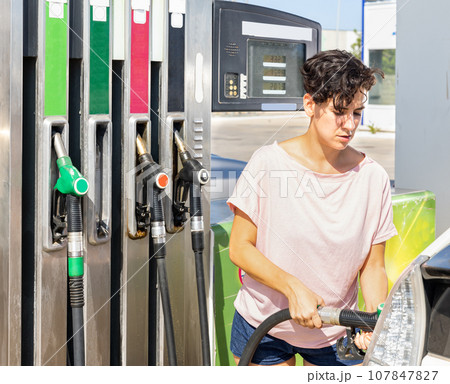 Smiling woman refueling her car in gas station Smiling woman refueling her car in gas station 107847827