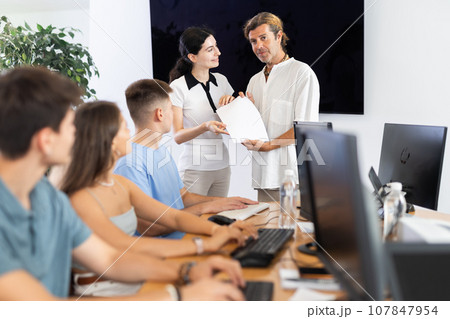 Among students of computer courses, male teacher awards diploma and to excellent girl pupil Among students of computer courses, male teacher awards diploma and to excellent girl pupil 107847954