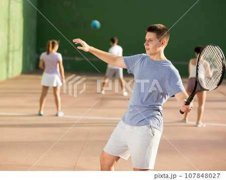 Young male pelota player hitting ball with racket 107848027