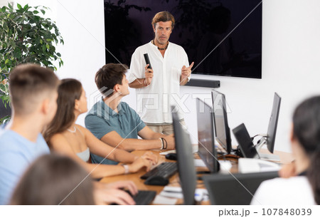 Adult man speaker stands in front of students and talks about use of artificial intelligence 107848039