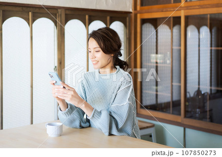 キッチンでスマホを見る女性 107850273
