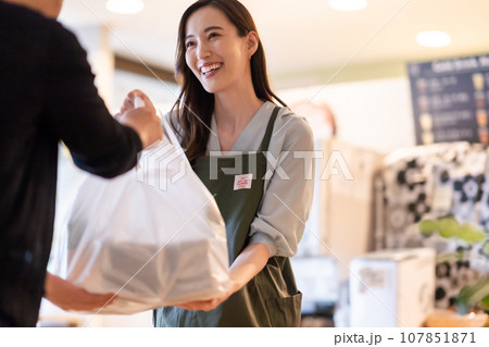 商品を手渡しする若い女性店員 107851871