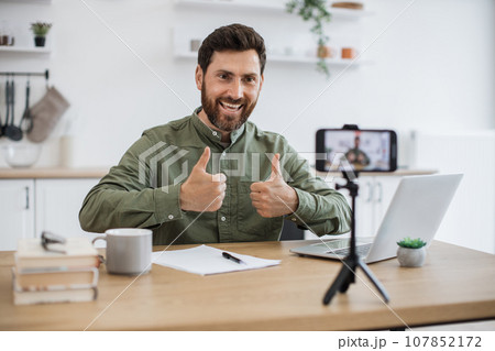Man working on laptop and recording video on smartphone Man working on laptop and recording video on smartphone 107852172
