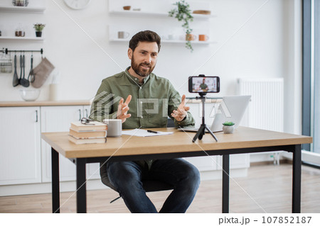 Man working on laptop and recording video on smartphone Man working on laptop and recording video on smartphone 107852187