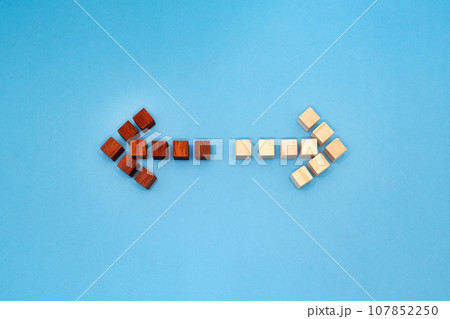 赤と黄色のウッドキューブの矢印が逆方向を指す青い背景の正面 107852250