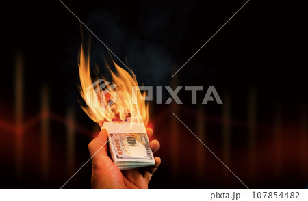 Burning money in hand on a dark background with copy space for text 107854482