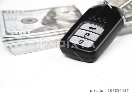 Car key with dollar banknotes on a white background with copy space below for text 107854487
