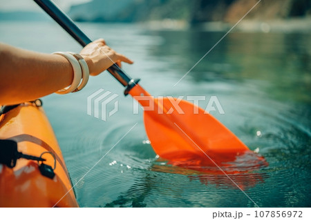 Kayak paddle sea vacation. Person paddles with orange paddle oar on kayak in sea. Leisure active lifestyle recreation activity rest tourism travel 107856972