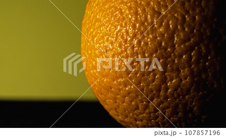 Close up of an orange on a yellow background with copy space. Close up of an orange on a yellow background with copy space. 107857196