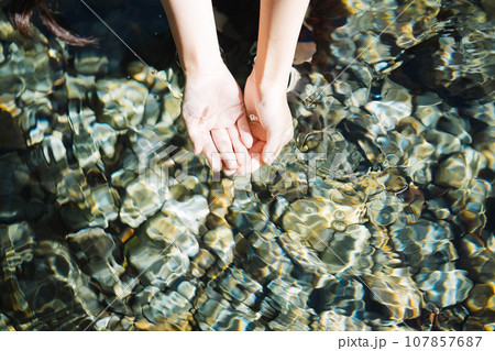 渓流の水をすくう若い女性 107857687