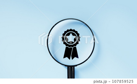 Magnifying glass focuses on quality warranty icon, quality assurance, ISO certification, and standardization concept. Compliance to regulations. blue background Magnifying glass focuses on quality warranty icon, quality assurance, ISO certification, and standardization concept. Compliance to regulations. blue background 107859525