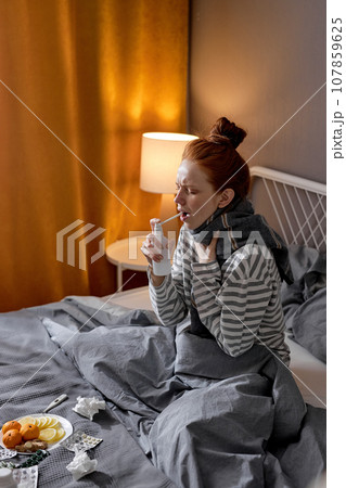 sick ginger woman with sore throat sprinkles medicine into mouth sick ginger woman with sore throat sprinkles medicine into mouth 107859625