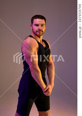 muscular handsome sportsman demonstrates his muscles muscular handsome sportsman demonstrates his muscles 107859799