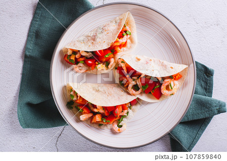 Close up of vegetarian mini tacos with tomatoes, shrimp and herbs on a plate top view 107859840