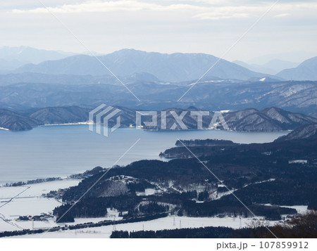 雪の山野に囲まれた大きな湖 (福島県、猪苗代町) 107859912