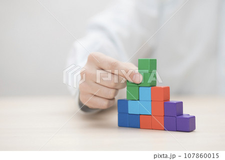 Man's hand stacking colorful wooden blocks. Business development concept Man's hand stacking colorful wooden blocks. Business development concept 107860015